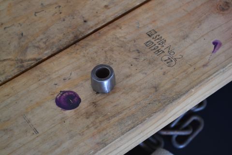 1981 Ford F-250 - A metal bushing and two purple ink marks sit on a wooden surface with stamped text.
