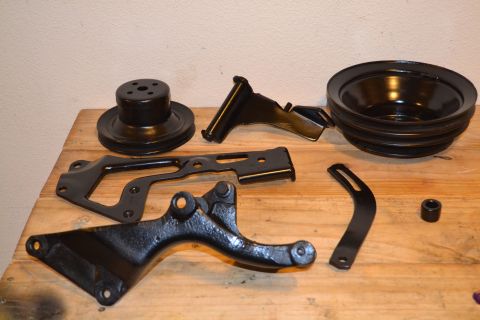 1981 Ford F-250 - Various engine pulleys and brackets are displayed on a wooden table.