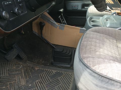 1991 Ford F-150 - The interior of a truck shows a floor shifter and a makeshift cardboard console modification.