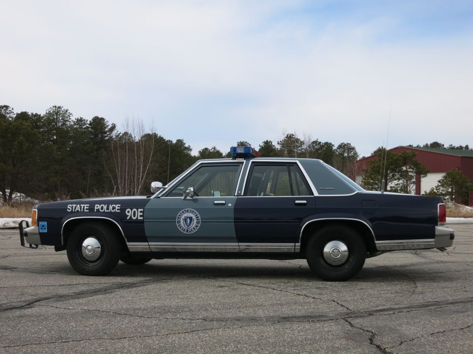 Massachusetts State Police Ford sedan, passenger-side profile with state seal