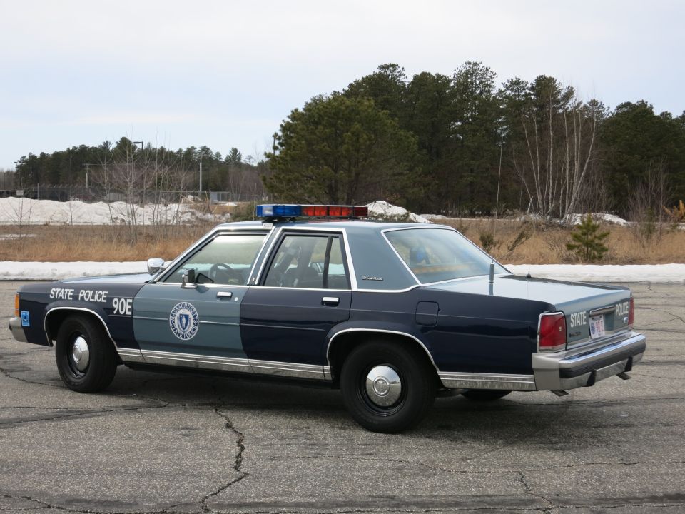 Massachusetts State Police Ford sedan, driver-side rear three-quarter view