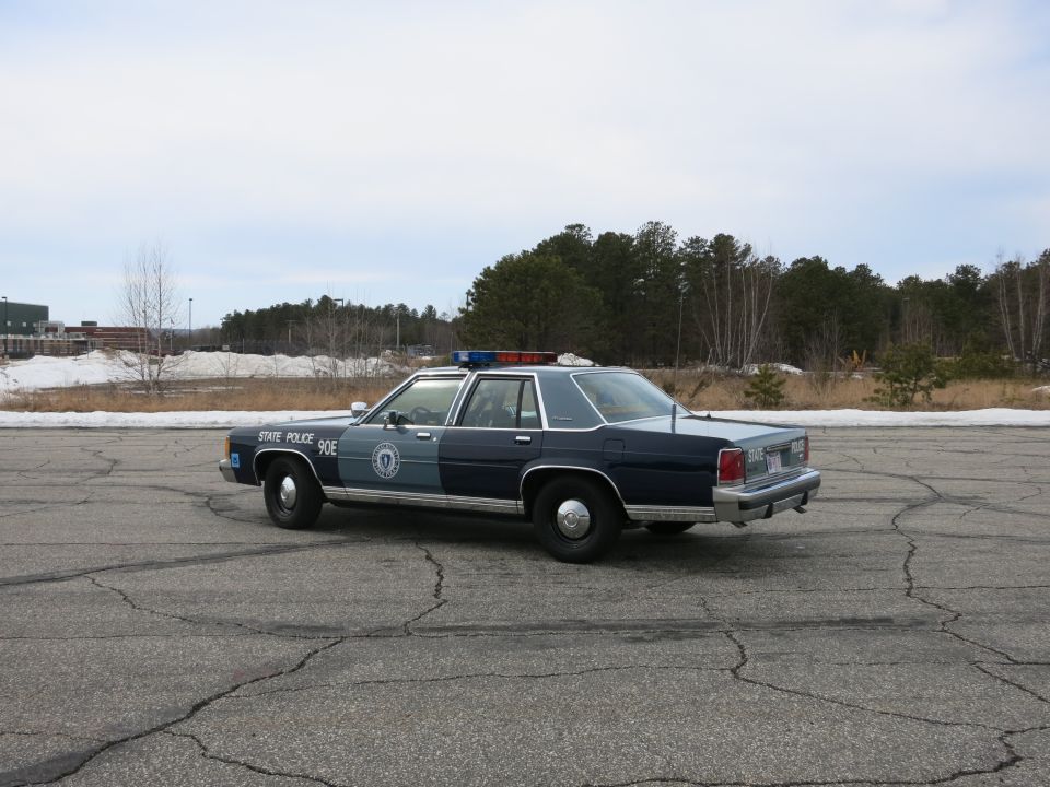 Massachusetts State Police Ford sedan, rear three-quarter view across paved lot