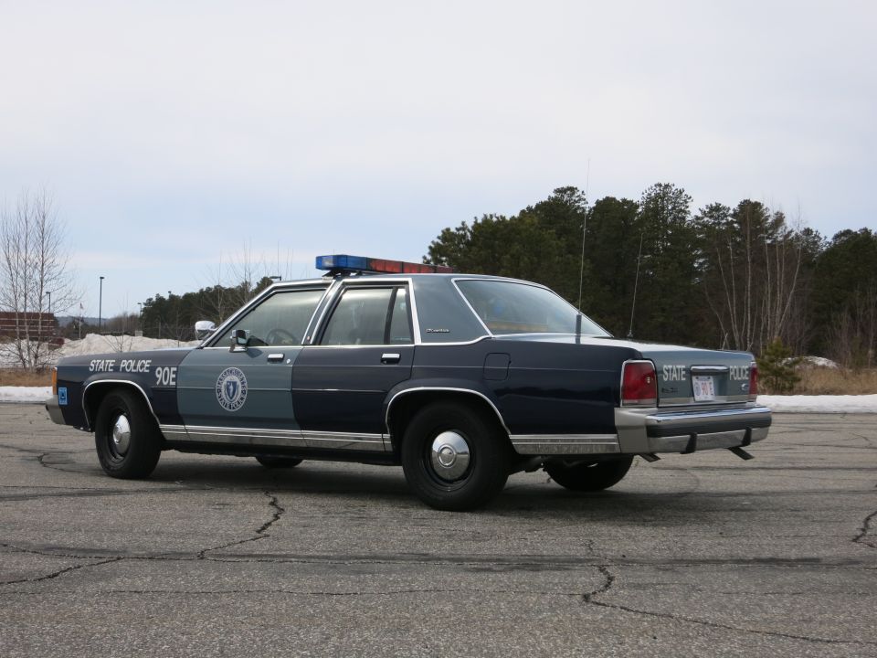 Massachusetts State Police Ford sedan, driver-side rear three-quarter view