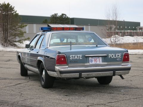 1991 Ford LTD Crown Victoria - Direct rear view of a two-tone Massachusetts State Police Ford cruiser showing STATE POLICE lettering, Ford badge and red MA plate.