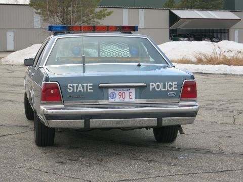 1991 Ford LTD Crown Victoria - Direct rear view of a two-tone blue Ford LTD Crown Victoria marked STATE POLICE with a Massachusetts plate and roof light bar.