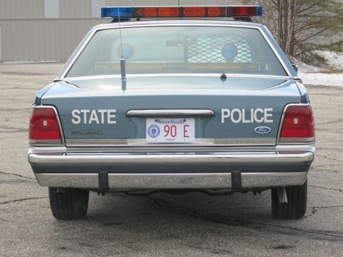 1991 Ford LTD Crown Victoria - Direct rear view of a two-tone blue Ford LTD Crown Victoria State Police cruiser with an illuminated roof light bar.