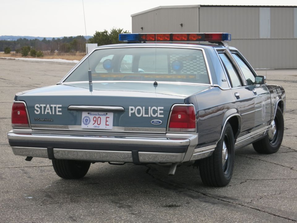 Rear three-quarter view of blue Ford Crown Victoria State Police cruiser