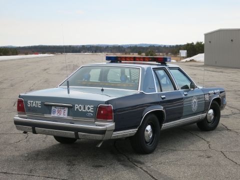 1991 Ford LTD Crown Victoria - Rear three-quarter view of a two-tone blue Ford LTD Crown Victoria State Police cruiser showing the round seal on the rear door.