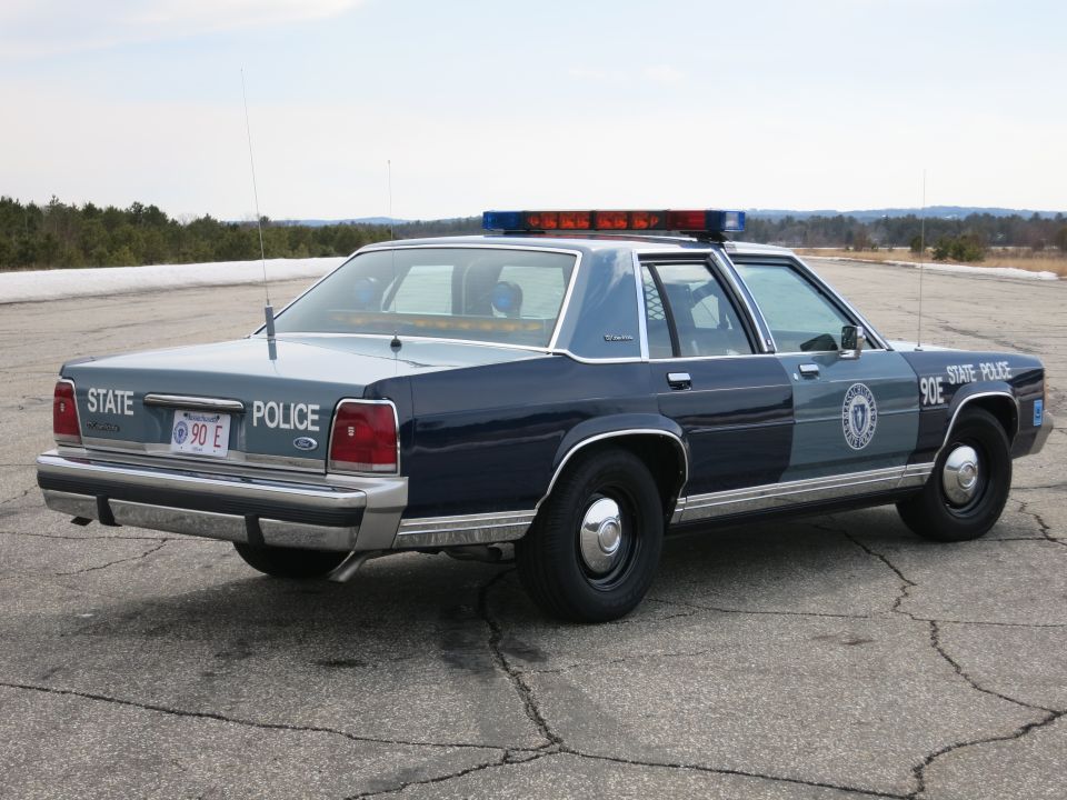 Rear three-quarter view of blue Ford Crown Victoria State Police cruiser, unit 90E