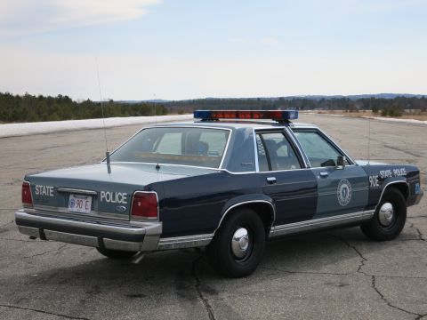 1991 Ford LTD Crown Victoria - Rear three-quarter view of a two-tone blue Ford LTD Crown Victoria State Police cruiser marked 90E with door seal and light bar.