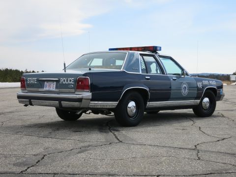 1991 Ford LTD Crown Victoria - Rear three-quarter view of a two-tone blue Ford LTD Crown Victoria State Police cruiser marked 90E with door seal and light bar.
