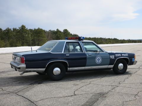 1991 Ford LTD Crown Victoria - Right side profile of a two-tone blue Ford LTD Crown Victoria State Police cruiser marked 90E STATE POLICE on a tarmac.