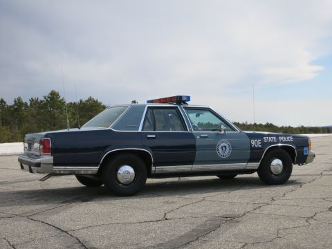 1991 Ford LTD Crown Victoria - Right side profile of a two-tone blue Ford LTD Crown Victoria State Police cruiser marked 90E with a roof light bar.