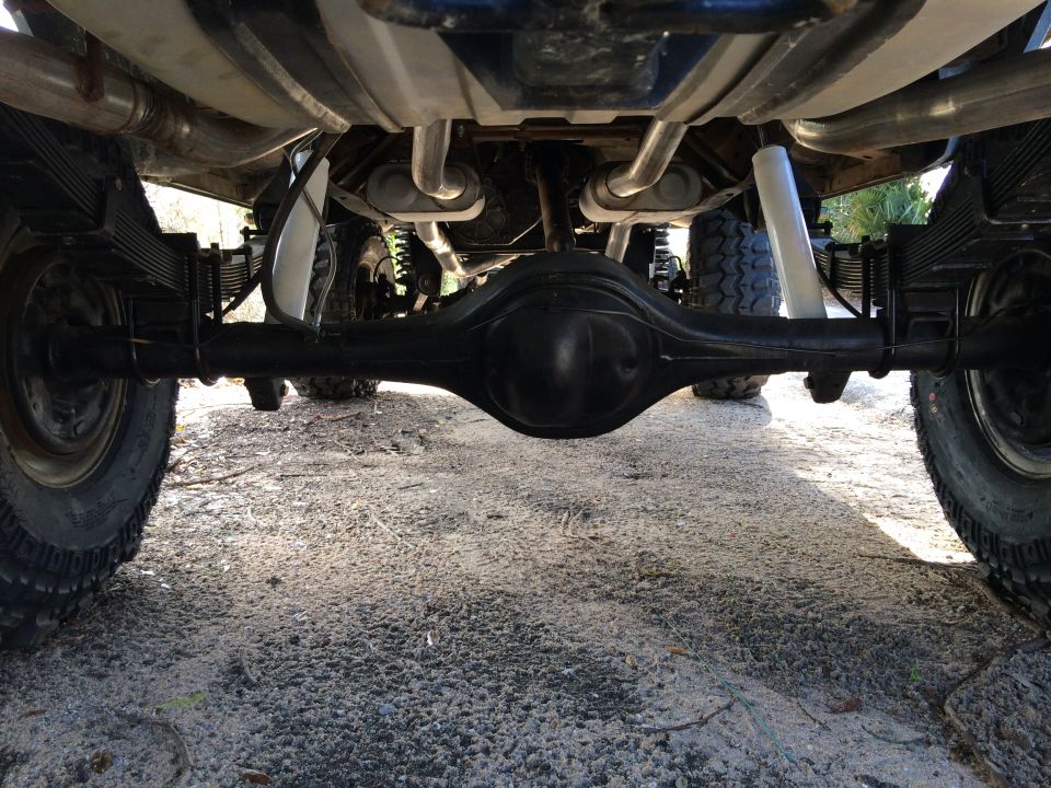 Rear axle, leaf springs, dual exhaust pipes, and shocks of a truck