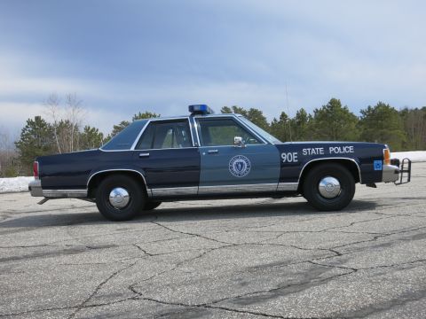 1991 Ford LTD Crown Victoria - blue Massachusetts State Police cruiser numbered 90E shown in profile with a front push bumper near snowbanks.