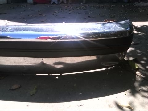1992 Ford Bronco - A chrome bumper with a black rubber strip is shown in a close-up outdoor shot.