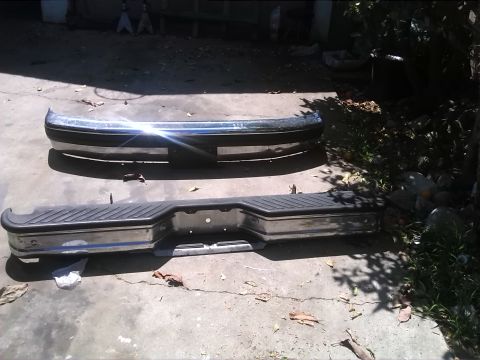 1992 Ford Bronco - Two vehicle bumpers are shown on a concrete surface outdoors.
