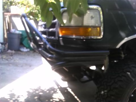 1992 Ford Bronco - Close-up of the front of a dark SUV, a brush guard and headlight assembly.