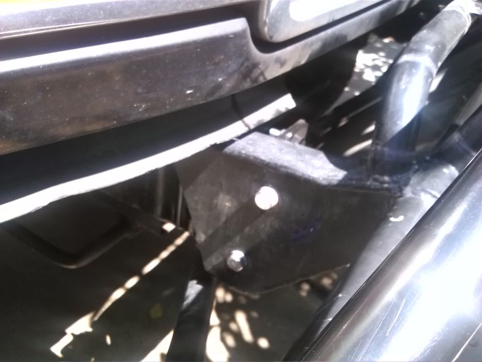 Undercarriage of a vehicle with a black rubber hose and metal brackets visible