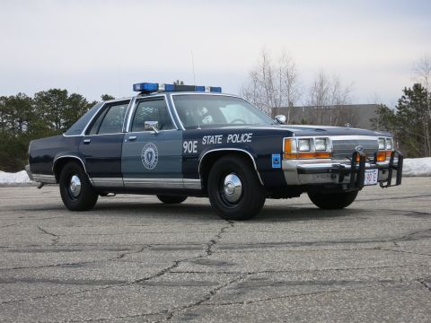 1991 Ford LTD Crown Victoria - two-tone blue State Police Ford sedan marked 90E shown front three-quarter with a chrome push bumper and red 90 E front plate.