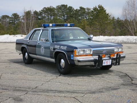 1991 Ford LTD Crown Victoria - two-tone blue State Police Ford sedan marked 90E shown front three-quarter with a Ford grille, push bumper and red 90 E front plate.