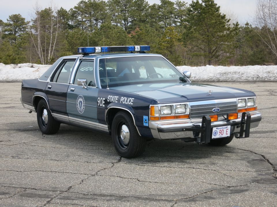 Massachusetts State Police Ford sedan with blue light bar, front three-quarter view