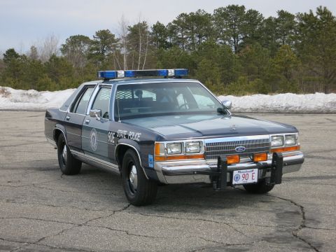 1991 Ford LTD Crown Victoria - Massachusetts State Police Ford LTD Crown Victoria marked STATE POLICE, photographed front-right on cracked asphalt.