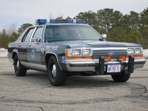 1991 Ford LTD Crown Victoria - two-tone blue Massachusetts State Police Ford LTD Crown Victoria with brush guard, parked near a snowbank and pine trees.