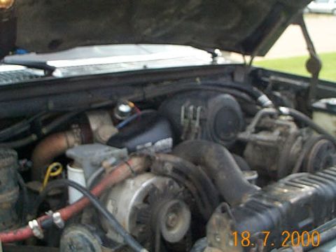 1986 Ford F-250 - The engine compartment of a truck is shown with various mechanical parts and hoses.