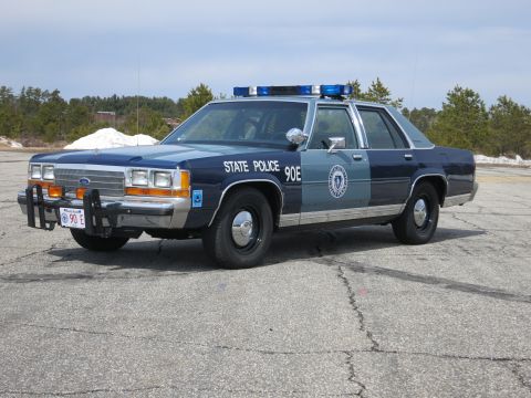 1991 Ford LTD Crown Victoria - Front three-quarter view of a two-tone blue Ford State Police cruiser with STATE POLICE 90E lettering and a roof light bar.