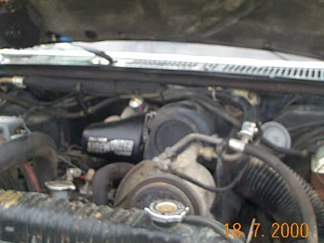 Diesel engine bay with hood open, hoses and fan shroud visible