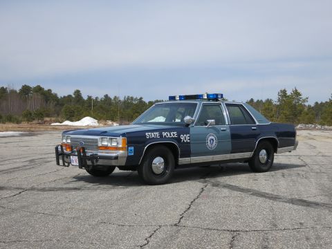 1991 Ford LTD Crown Victoria - Two-tone blue Ford State Police cruiser marked STATE POLICE 90E with push bumper, photographed at a front three-quarter angle.