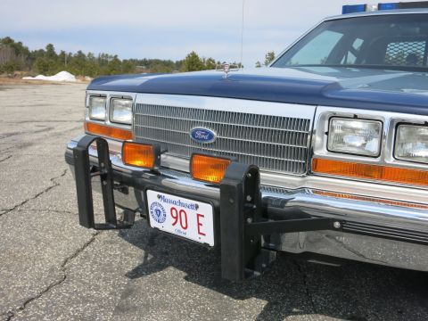 1991 Ford LTD Crown Victoria - Front detail of a Ford police car showing the chrome grille with Ford emblem, black push bumper and a Massachusetts plate reading 90 E.