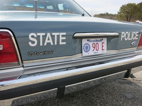 1991 Ford LTD Crown Victoria - Angled rear view of a gray Ford LTD Crown Victoria police cruiser lettered STATE POLICE with a Massachusetts 90 E plate.
