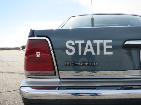 1991 Ford LTD Crown Victoria - Trunk lid of a dark gray police car lettered STATE with a Ford LTD Crown Victoria badge and taillight.