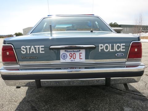 1991 Ford LTD Crown Victoria - Full rear view of a gray Ford LTD Crown Victoria police cruiser lettered STATE POLICE with a Massachusetts 90 E plate.