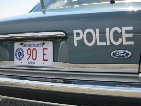 1991 Ford LTD Crown Victoria - Rear of a dark gray police car showing POLICE lettering, a Ford oval badge, and a Massachusetts Official 90 E license plate.