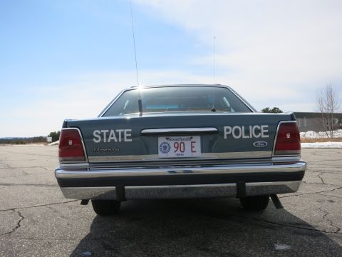 1991 Ford LTD Crown Victoria - Straight-on rear view of a gray Ford LTD Crown Victoria police cruiser lettered STATE POLICE with a 90 E plate.