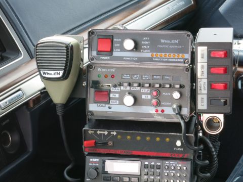 1991 Ford LTD Crown Victoria - Close-up of Whelen Traffic Advisor and siren control heads with a microphone and Code 3 radio mounted in a car center console.