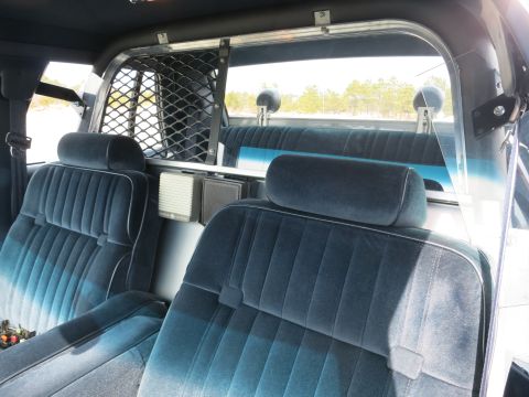 1991 Ford LTD Crown Victoria - Blue cloth front and rear seats with a metal prisoner cage partition and speaker box inside a police car.