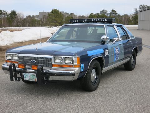 1991 Ford LTD Crown Victoria - two-tone blue Ford LTD Crown Victoria police cruiser marked 90E with an OUT OF SERVICE lightbar and push bumper, parked outdoors with snow…