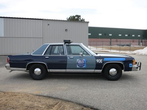 1991 Ford LTD Crown Victoria - Full passenger-side profile of a two-tone blue Ford LTD Crown Victoria police cruiser marked 90E with a NOT IN SERVICE door decal.