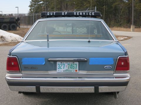 1991 Ford LTD Crown Victoria - Direct rear view of a blue Ford LTD Crown Victoria police cruiser showing badging, OUT OF SERVICE lightbar and a New Hampshire plate.