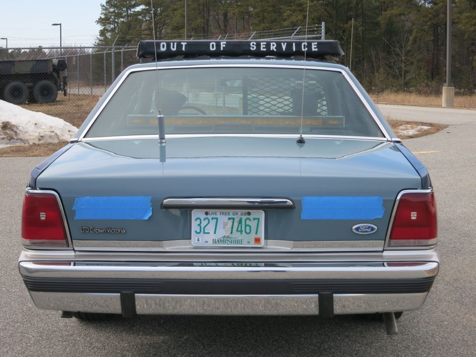 Rear of blue Ford LTD Crown Victoria police car with OUT OF SERVICE lightbar