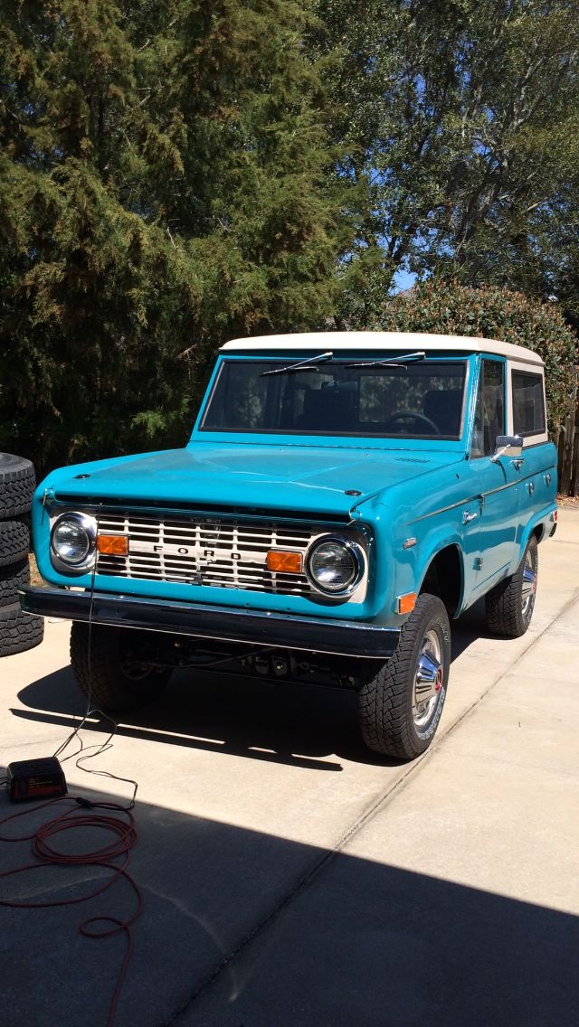 Blue 1968 Ford Bronco with white roof and chrome grille parked on a driveway