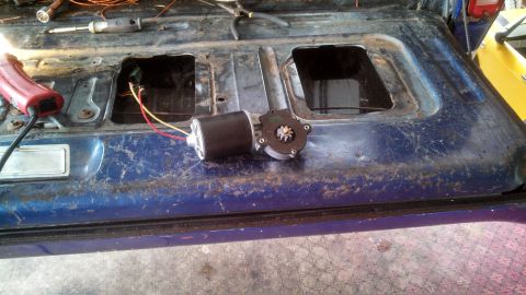 1979 Ford Bronco - The interior of a blue tailgate shows a removed window motor and wiring, with tools nearby.