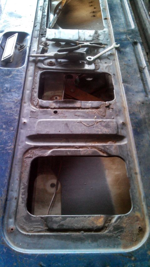 1979 Ford Bronco - Tools are laid out on the interior of a car door panel, which has two large openings.