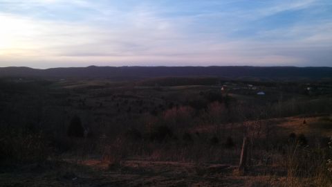 1979 Ford Bronco - A wide view of a rural landscape under a twilight sky, with some distant structures visible.