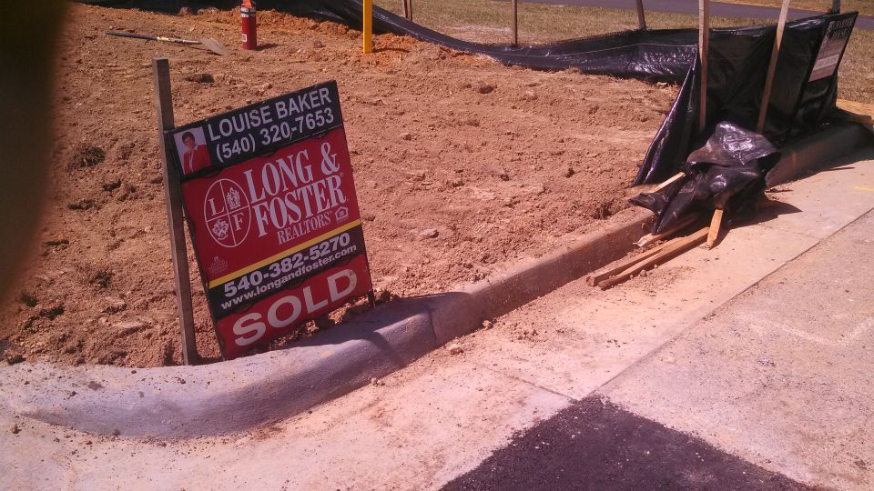 Sold real estate sign with Long & Foster Realtors branding on a dirt lot