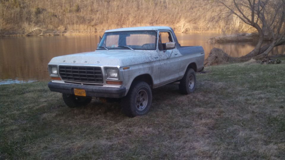 Ford Bronco parked by a body of water. It has a yellow license plate